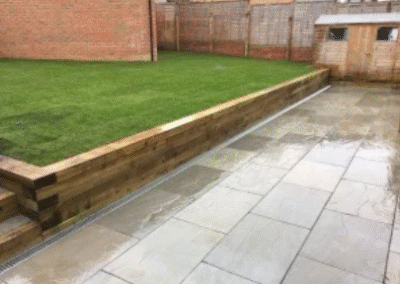 Garden with raised lawn, timber retaining wall, and paved patio area