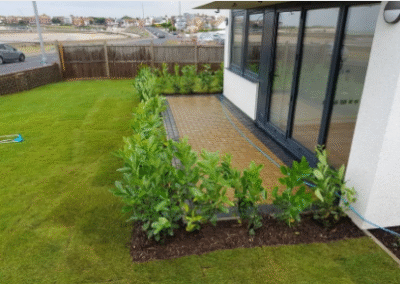 Newly landscaped garden with fresh turf and patio beside modern house