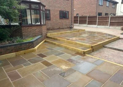 Newly installed stone patio with raised wooden edging in residential garden
