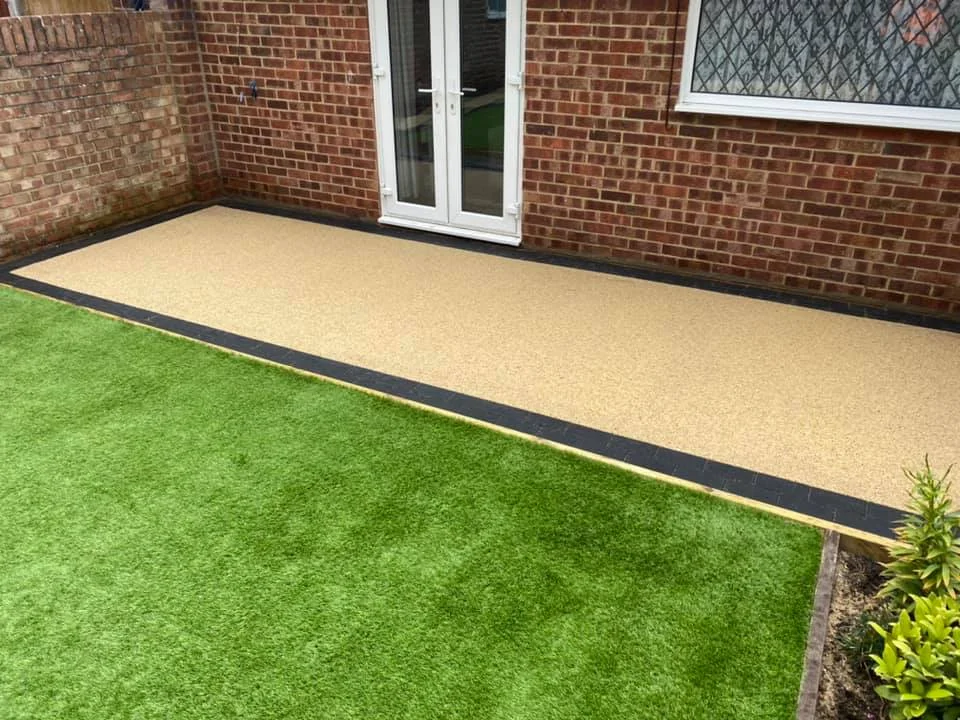 Resin bound patio with artificial grass in modern brick garden